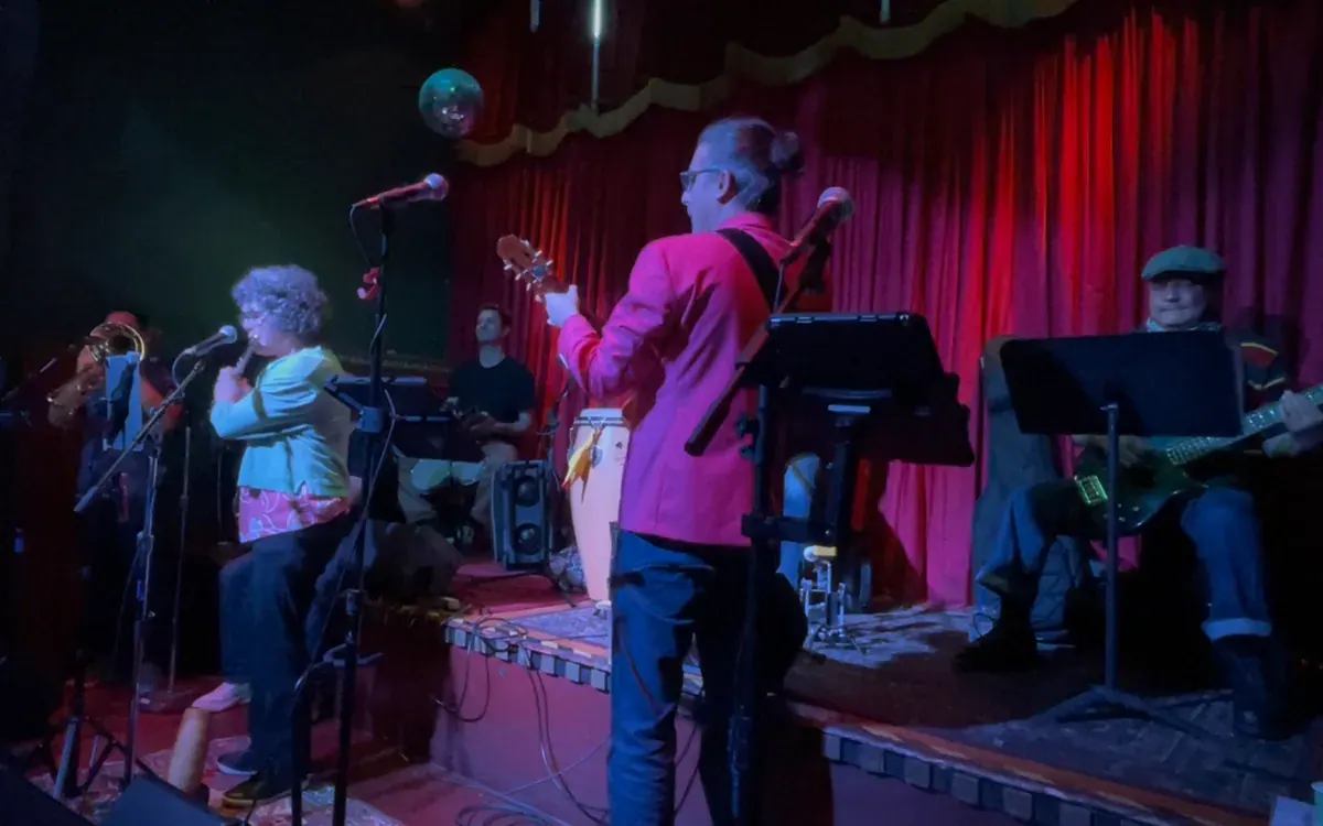 Guajirón performing onstage in front of red curtains